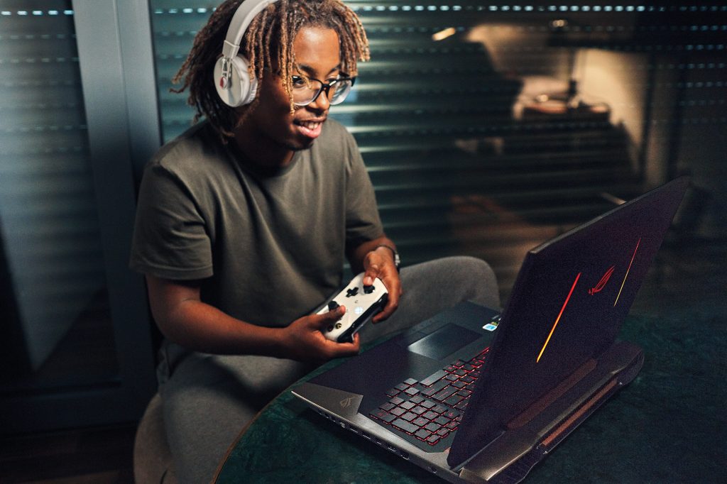 Boy wearing headphones and holding an Xbox controller gaming on a PC.