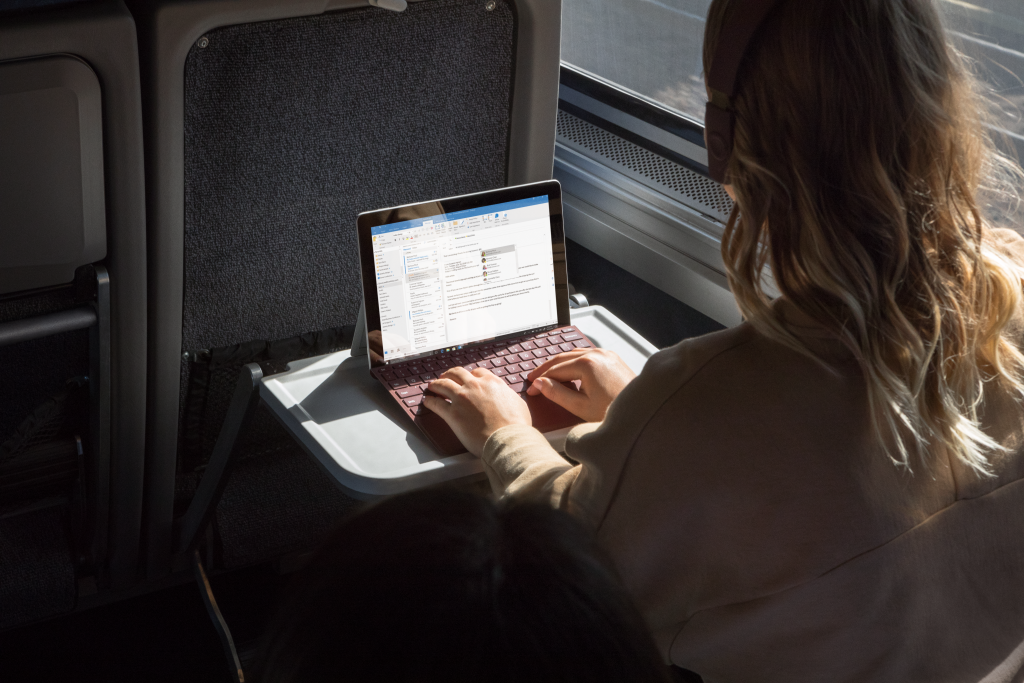 Woman on a train working on a Surface Go