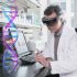 Man and woman in lab wearing HoloLens looking at a hologram of a DNA strand.