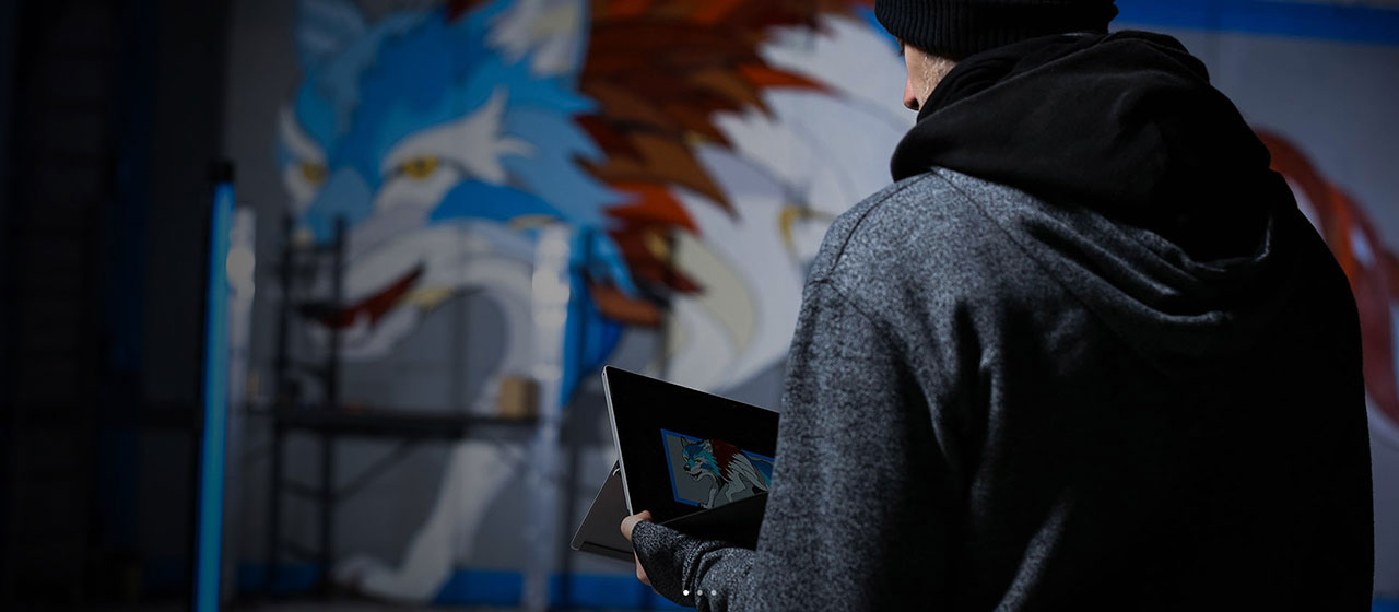 Mural artist Andrei working on his art with Surface Pro 4.