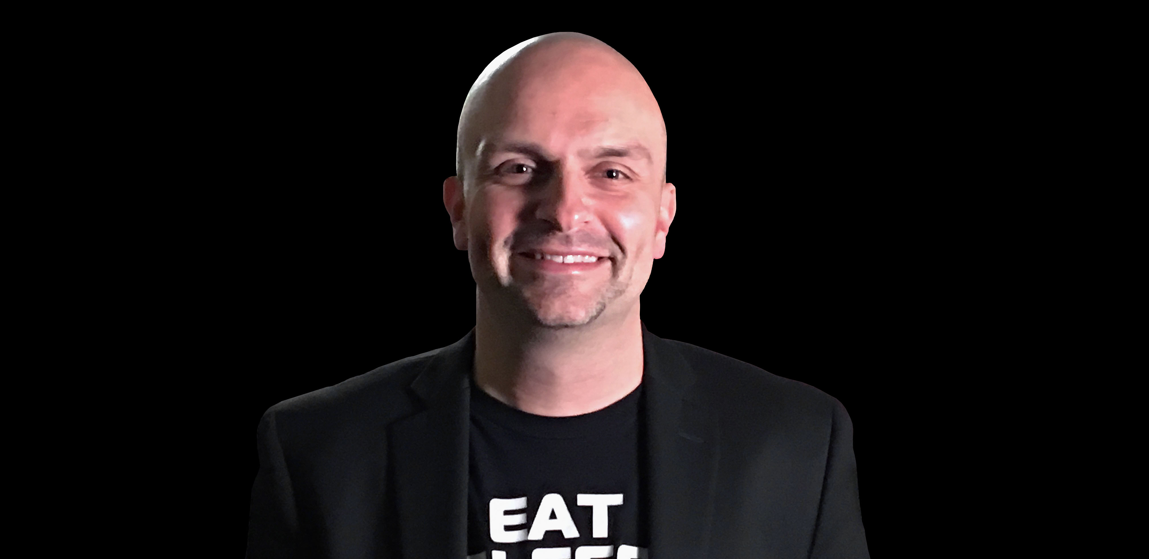 Photo of ORIGIN PC co-founder Kevin Wasielewski wearing a black t-shirt and black jacket against a black background