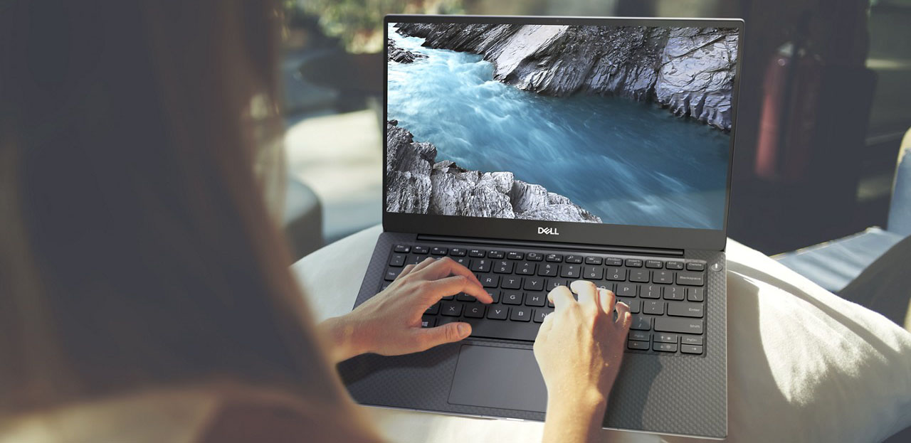 Photo of a woman working on a Dell XPS 13, from behind, with her hands on the keyboard