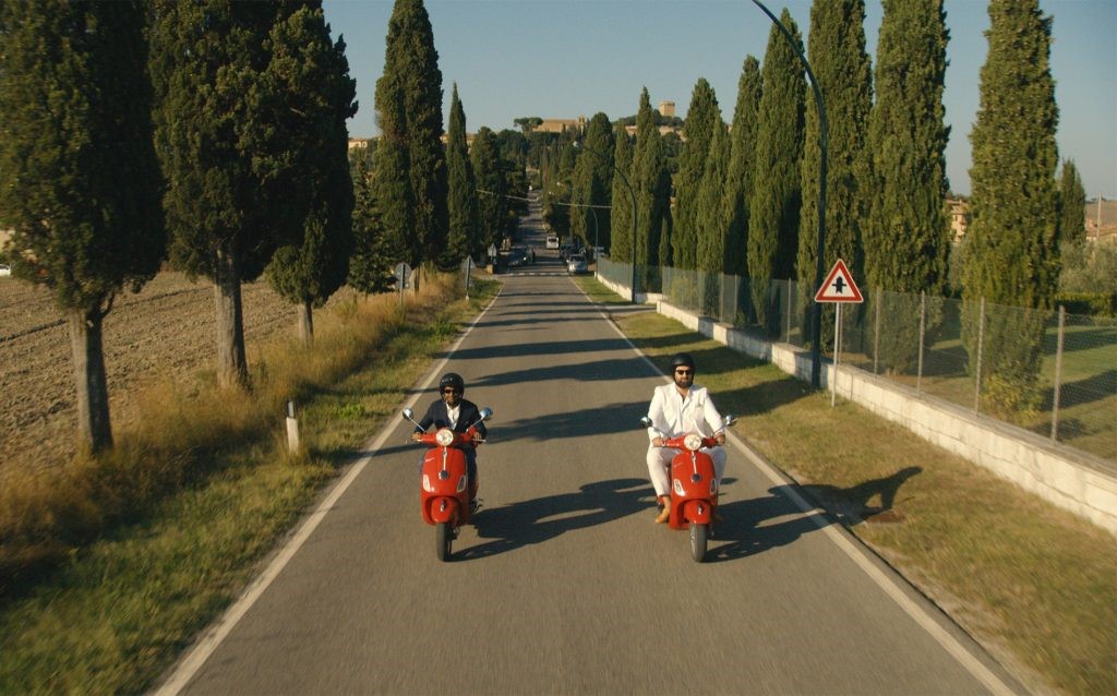 From the Netflix show, Master of None, two men riding scooters down a road.
