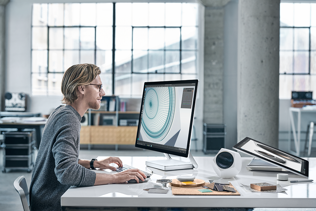 Man sitting at desk in an office using Surface Studio.