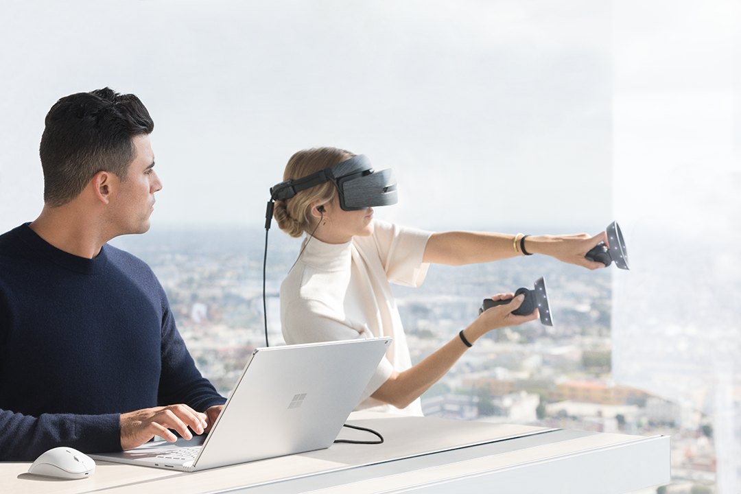 Woman wearing Windows Mixed Reality headset running on Surface Book 2