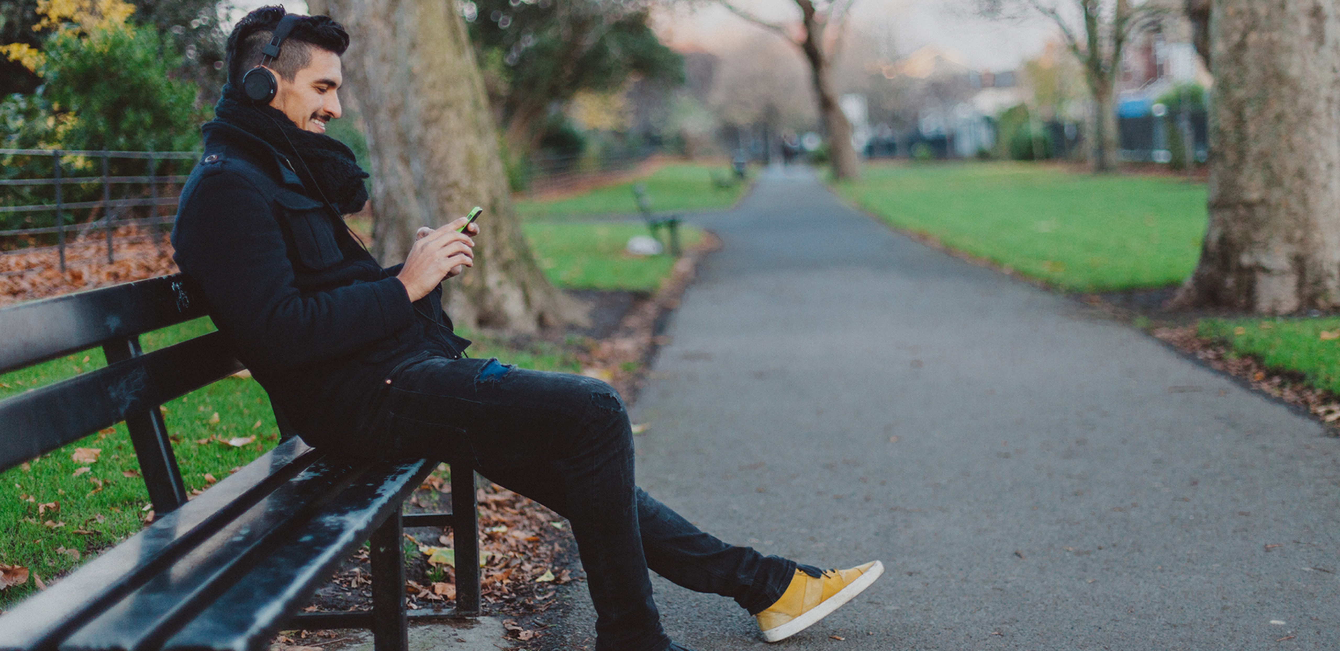 Man sitting on park bench, looking at a phone