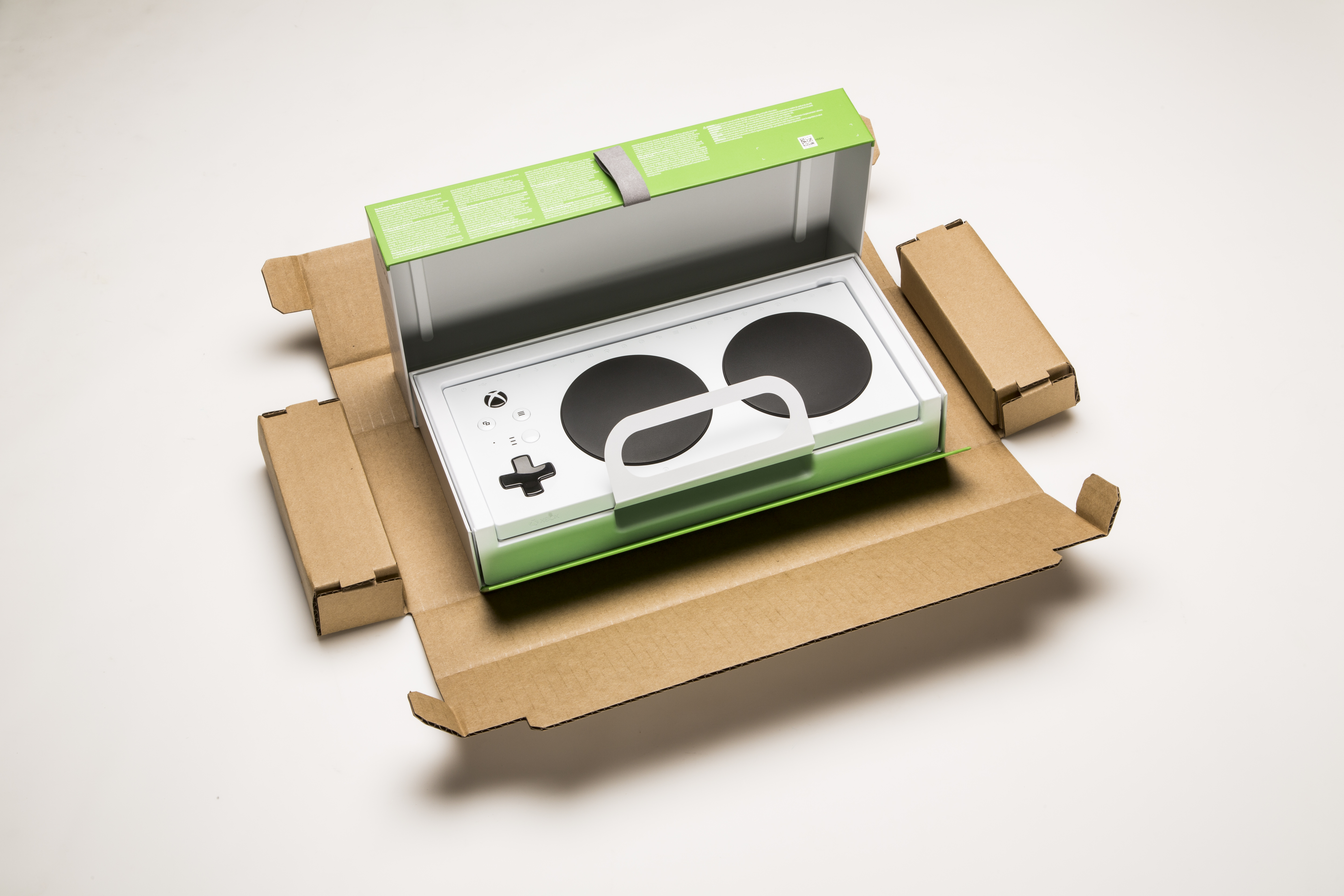 The new Xbox Adaptive Controller, surrounded by the open box designed specifically to accommodate gamers with limited mobility