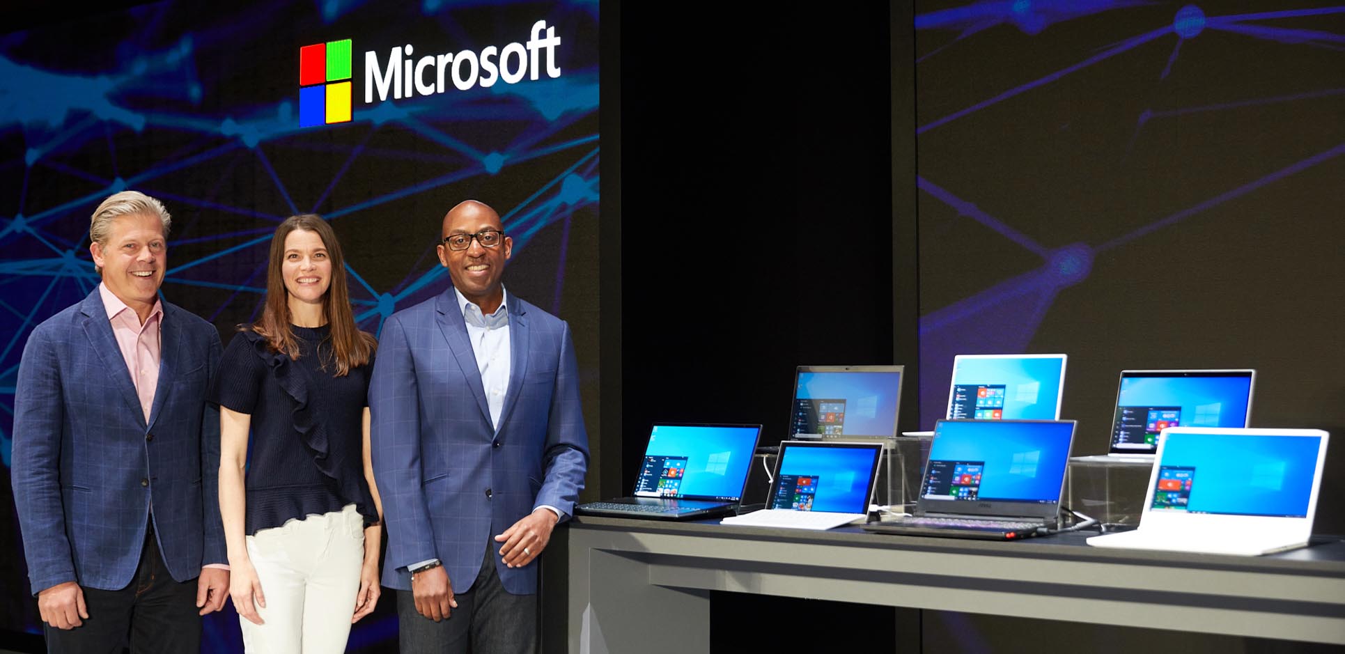 Nick Parker, Roanne Sones and Rodney Clark standing on a stage at Computex 2019 next to a table of PC laptops