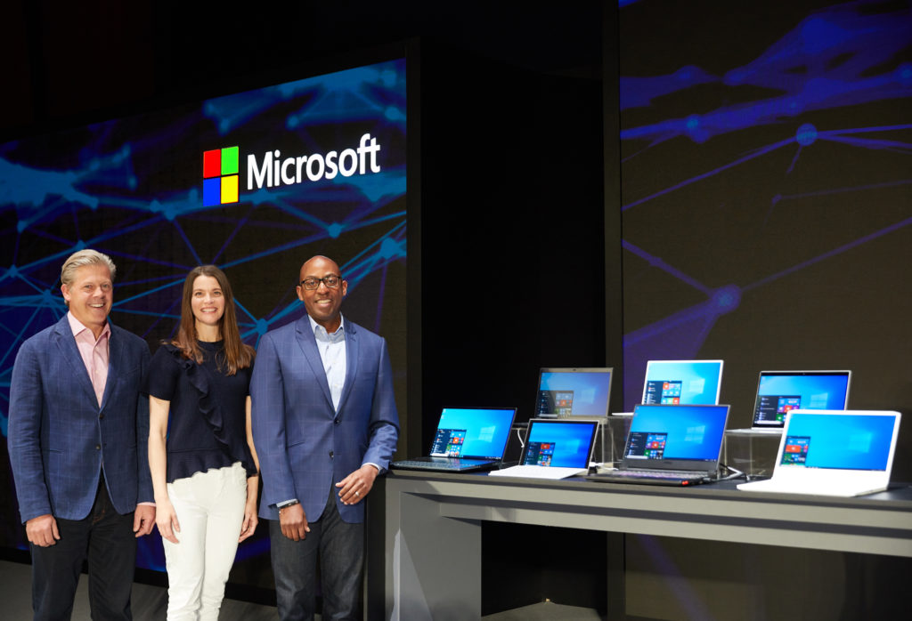 Nick Parker, Roanne Sones and Rodney Clark standing on a stage at Computex 2019 next to a table of PC laptops