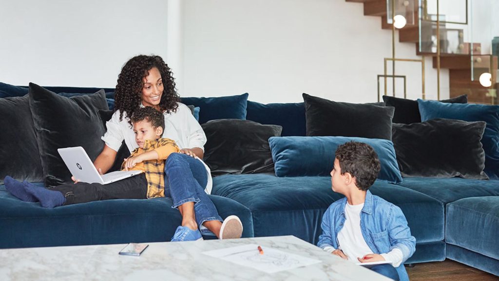Woman sitting on a couch with her 2 children and laptop
