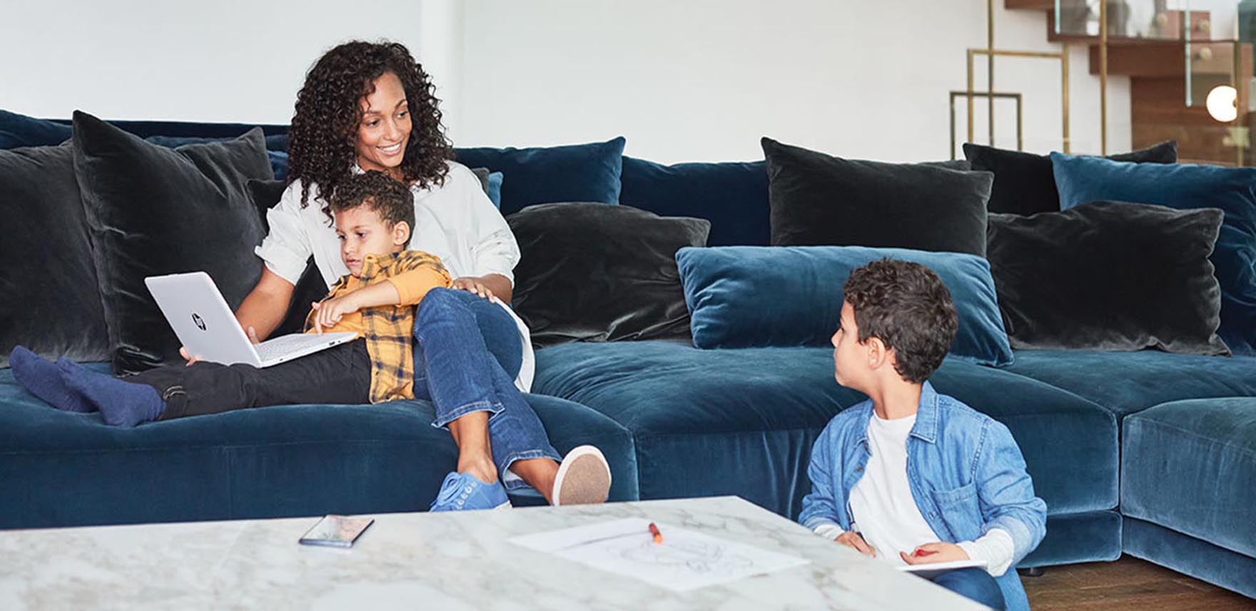 Woman sitting on a couch with her two children and laptop