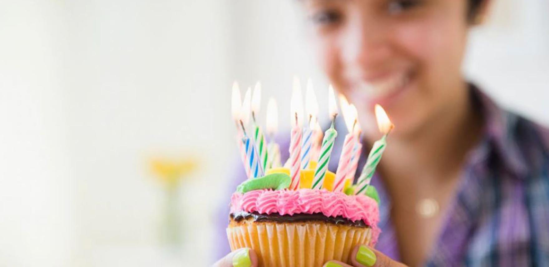 Woman holding a cupcake with birthday candles