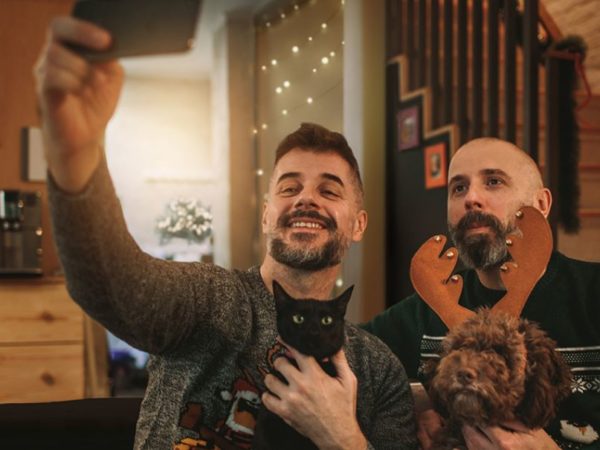 Two men pose for a selfie with their cat and dog