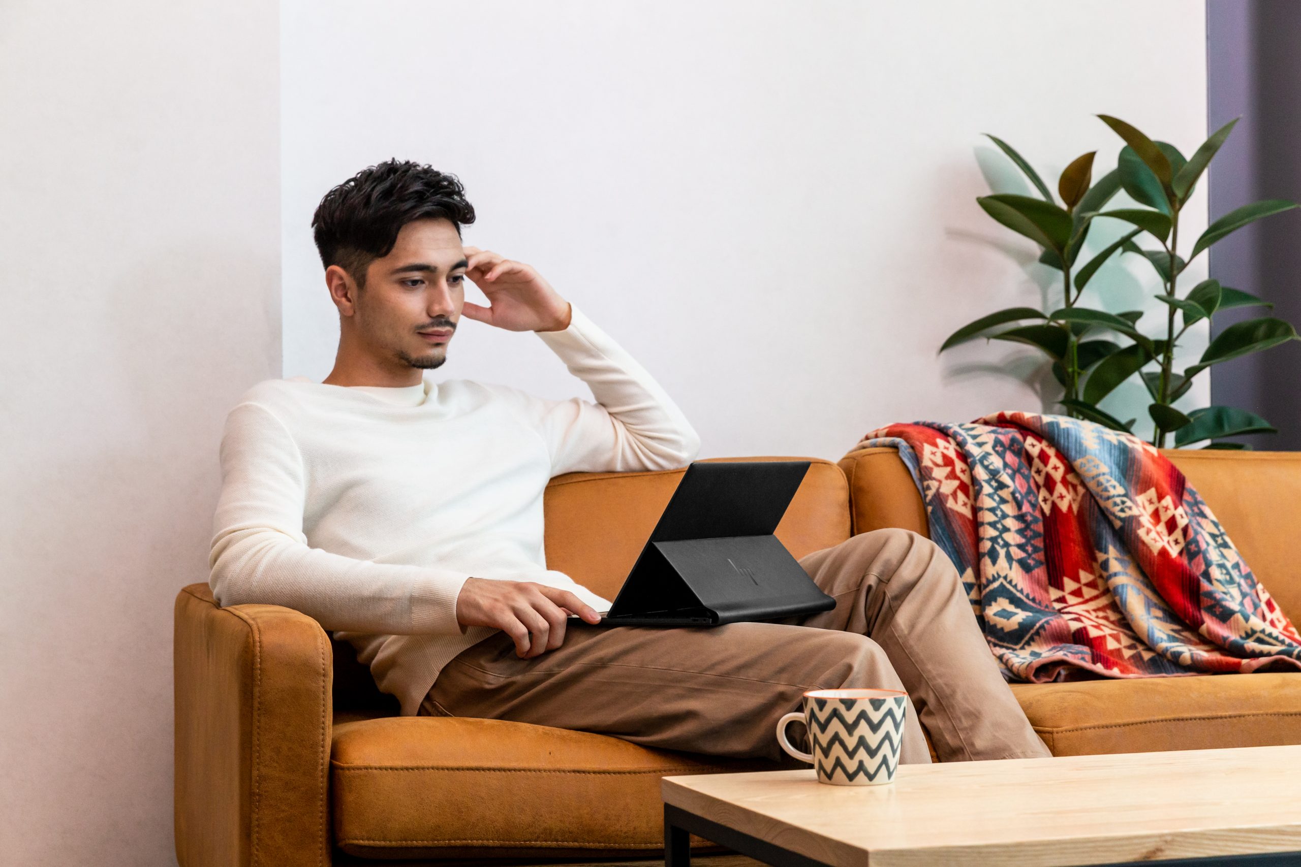 Man looking at HP Elite Folio on couch, with stand open
