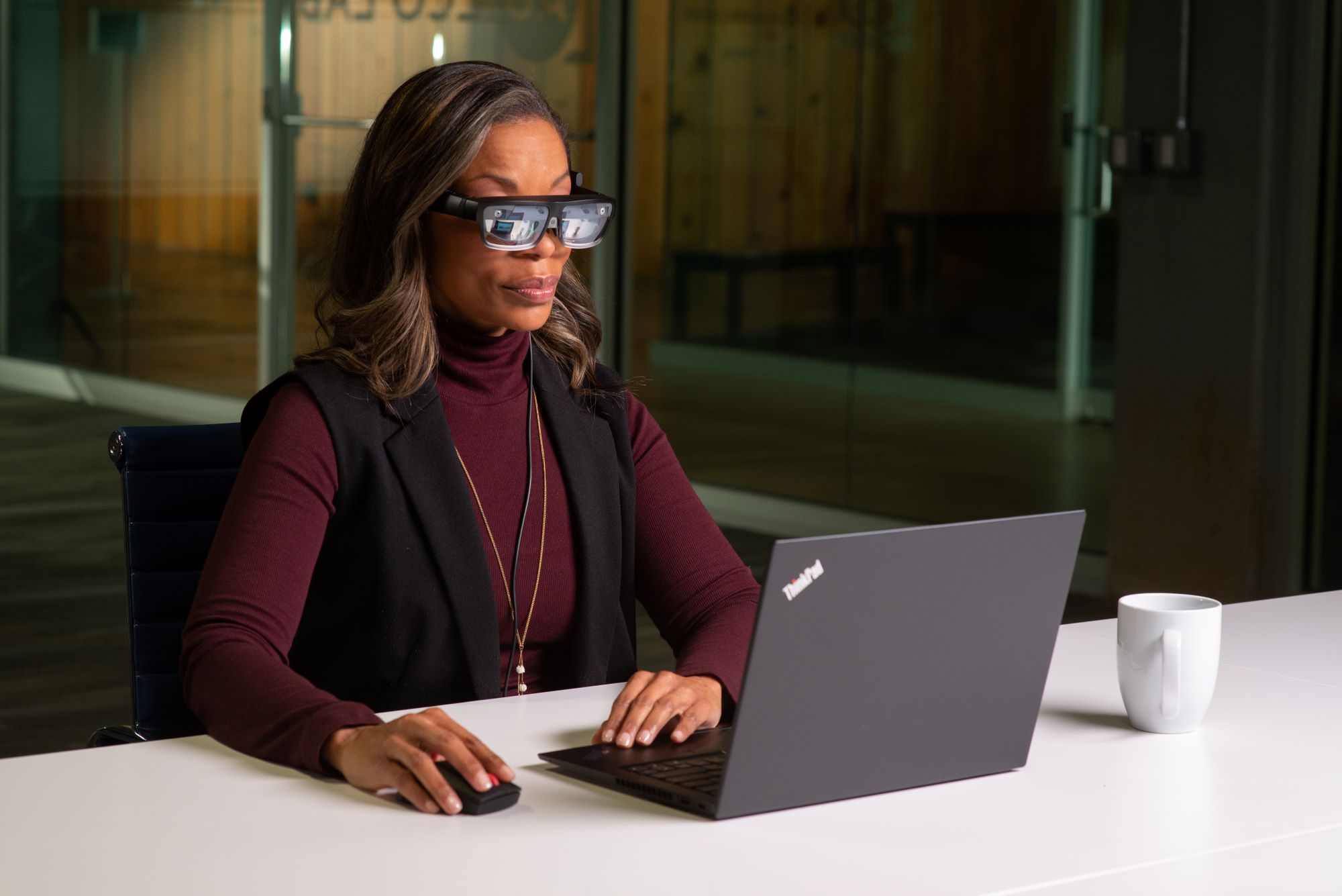 Woman wearing ThinkReality A3 glasses sitting in front of a Lenovo laptop