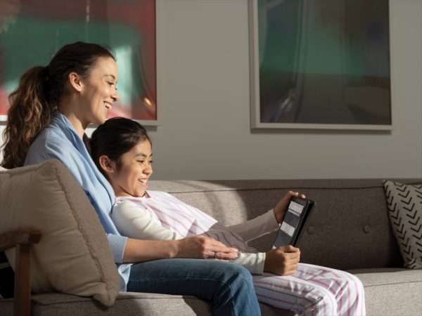 Child sitting on mother's lap looking at a mobile device