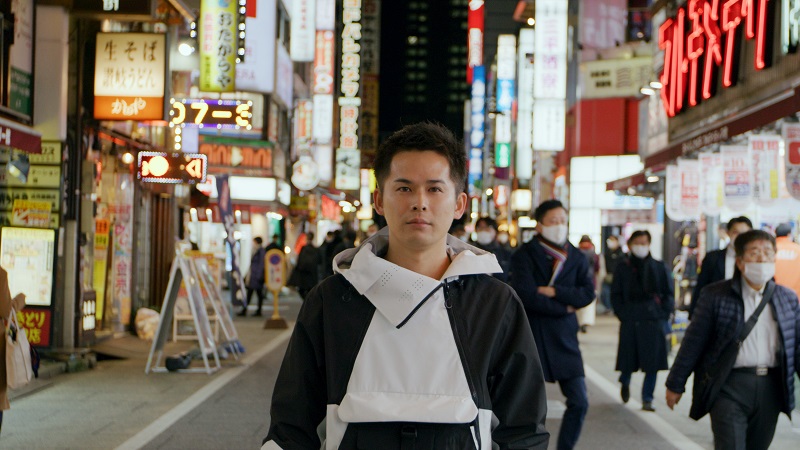 Ryogo Toyoda standing in the middle of a busy city at night