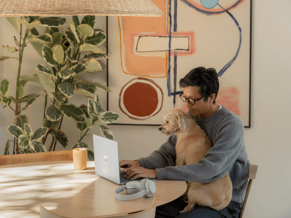 Man working on a Surface Laptop 4 device with a dog in his lap