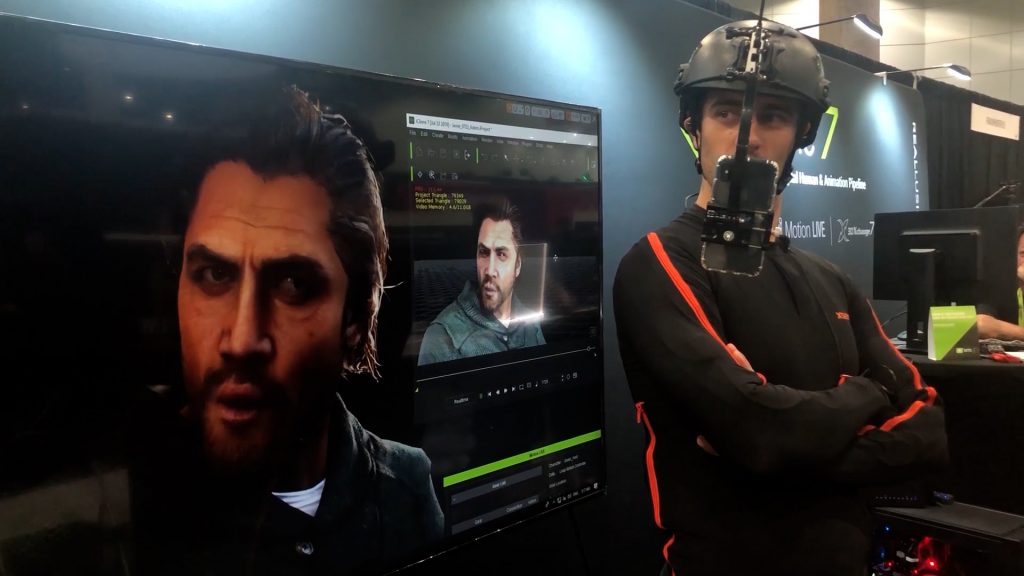Man in a mocap headgear next to a large display screen with an animated version