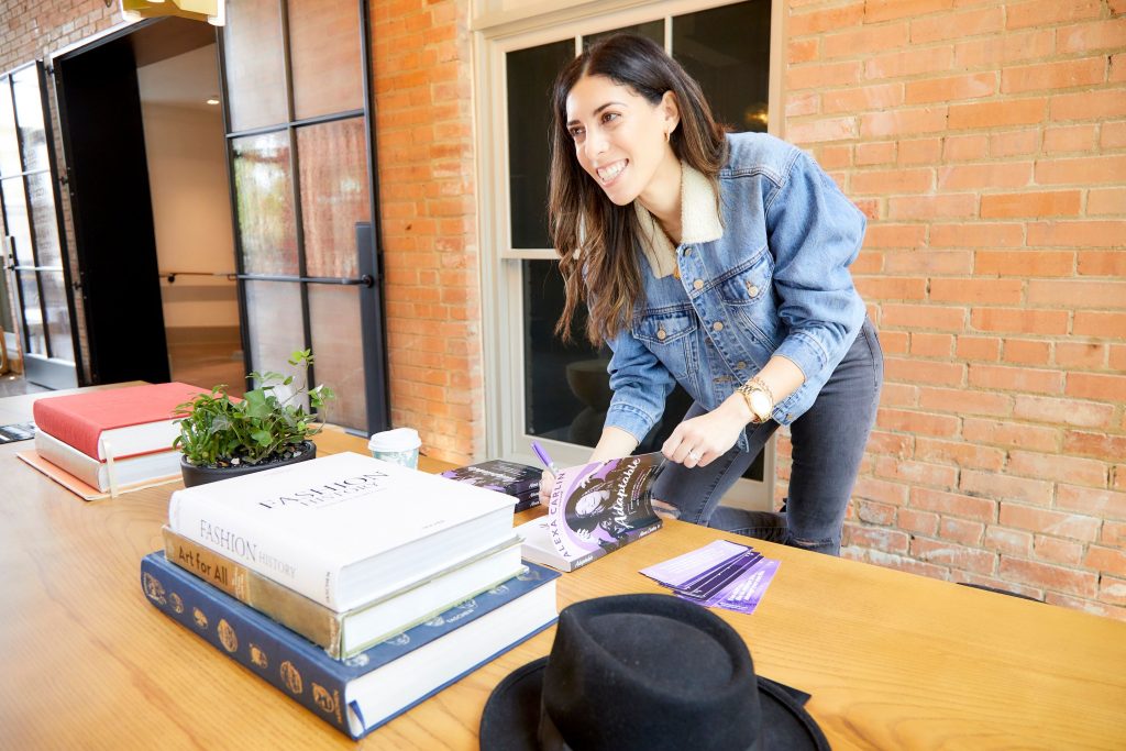 Woman signing books while standing up, bent over table