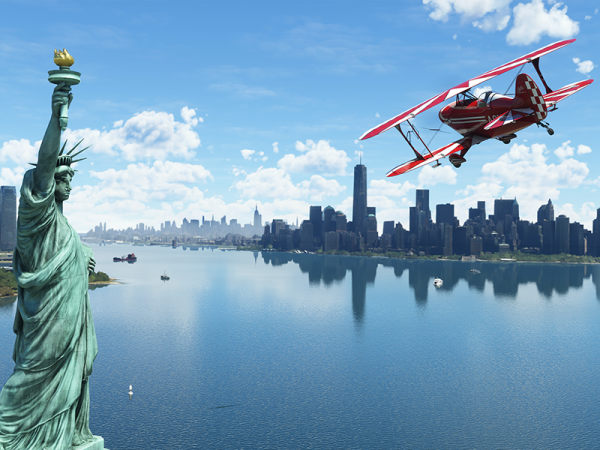 Red and white biplane approaches the Statue of Liberty