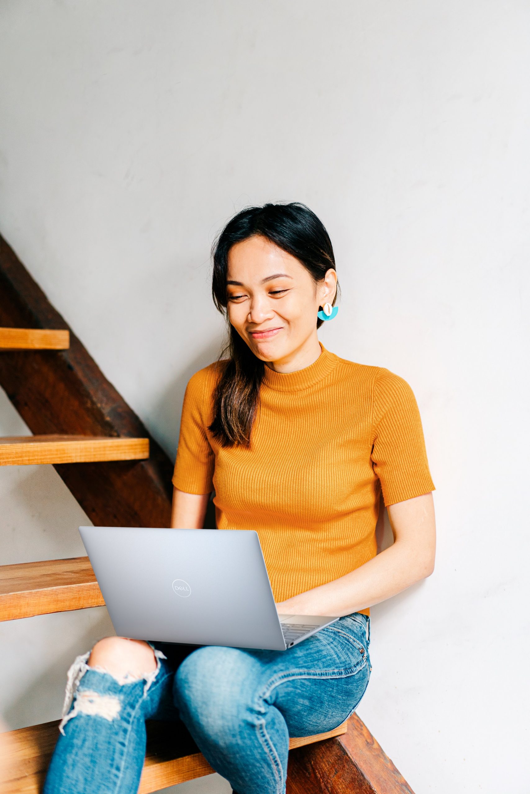 Woman sitting on stairs looking down at laptop