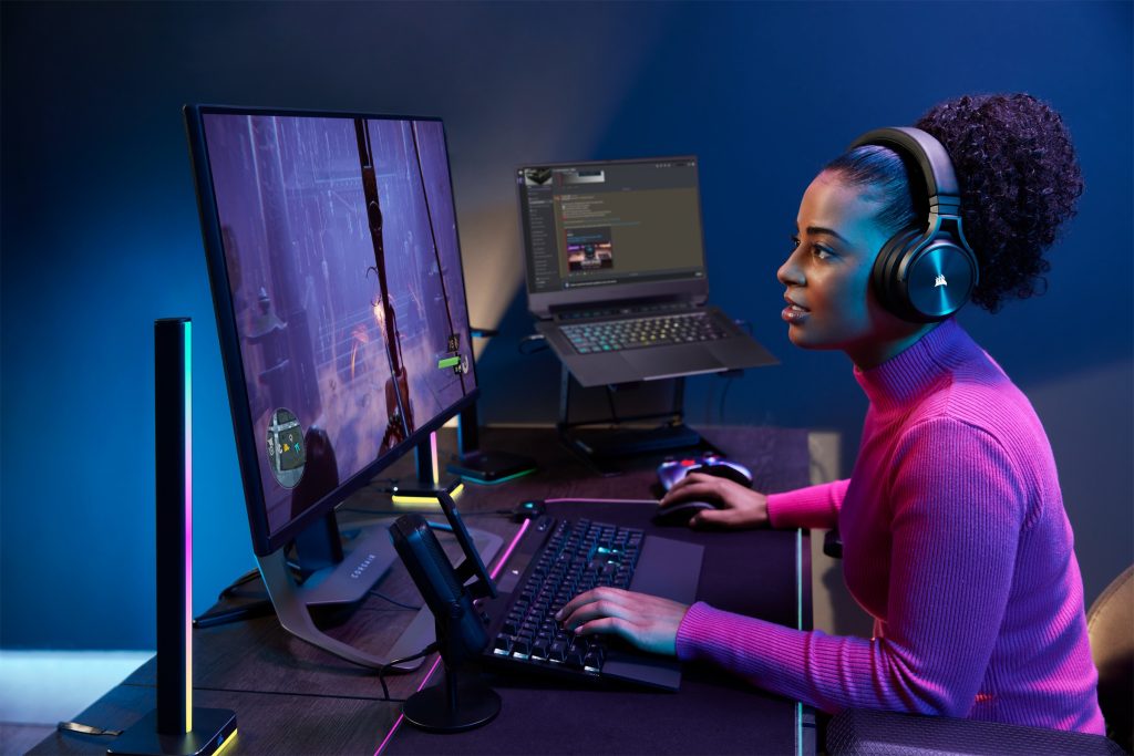 Woman sitting in a dark room gaming in front of a large monitor