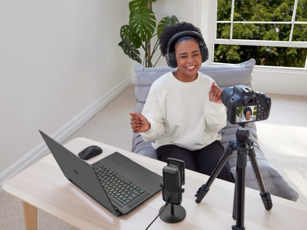 Woman talking to a camera on a tripod on a table next to a laptop