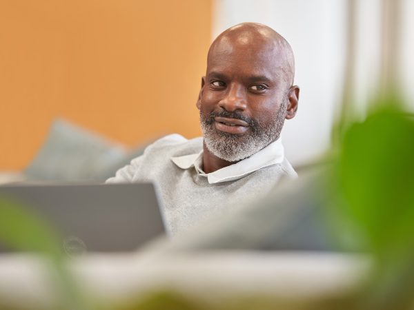 Man looking off camera as he sits at a laptop computer