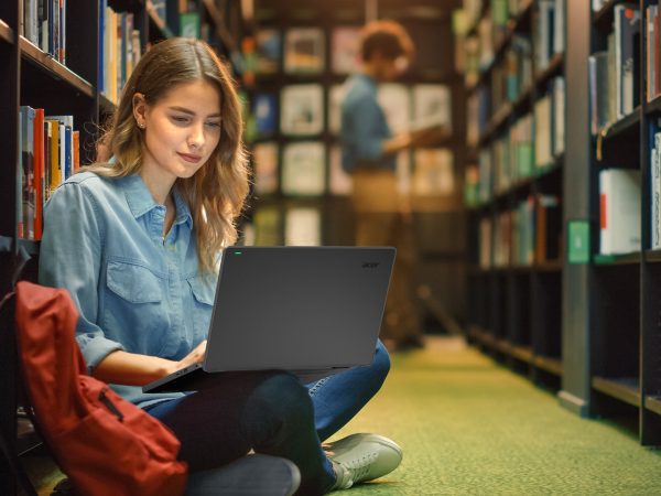 Woman sitting on floor of library with laptop