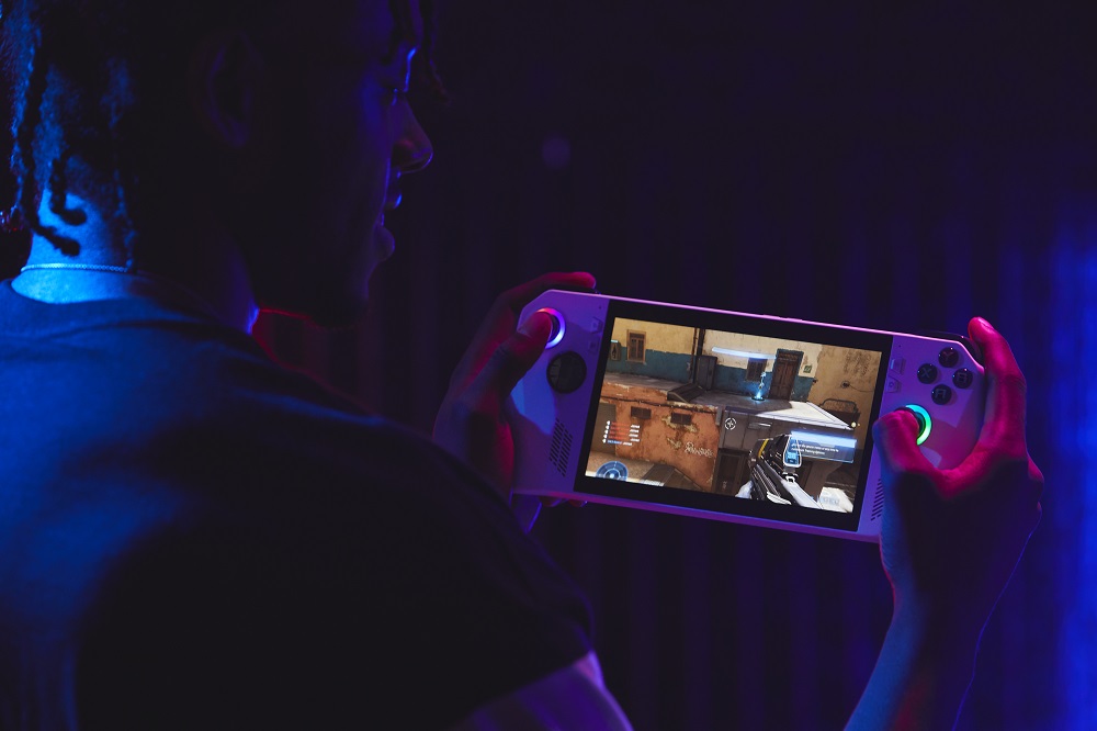 Man holding a handheld gaming console in the dark
