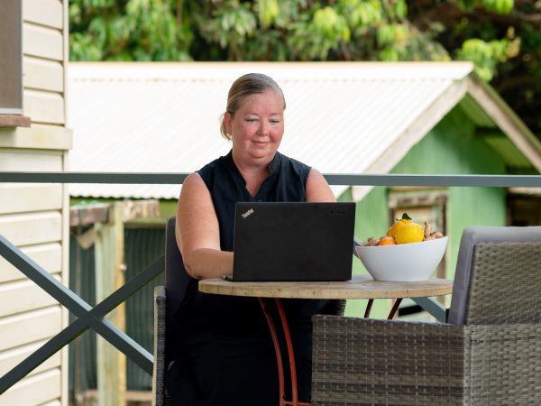 Aletha Thomas sitting on her patio working on her Lenovo laptop
