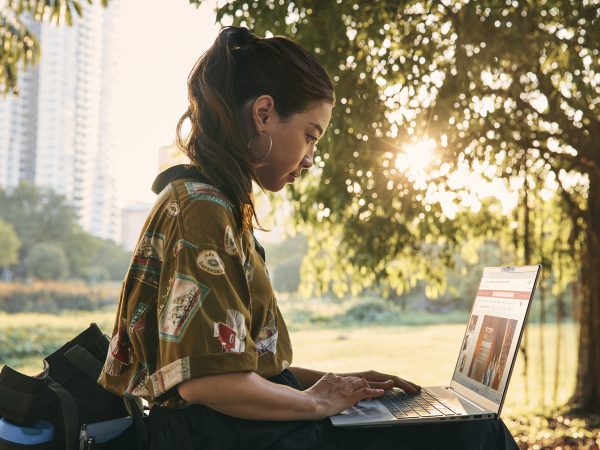 Profile of woman sitting outside working on a laptop computer
