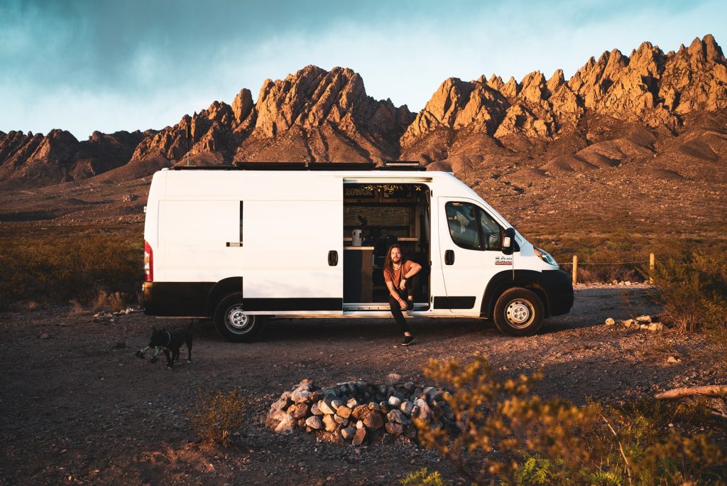 Man in a van, door open and desert in the background