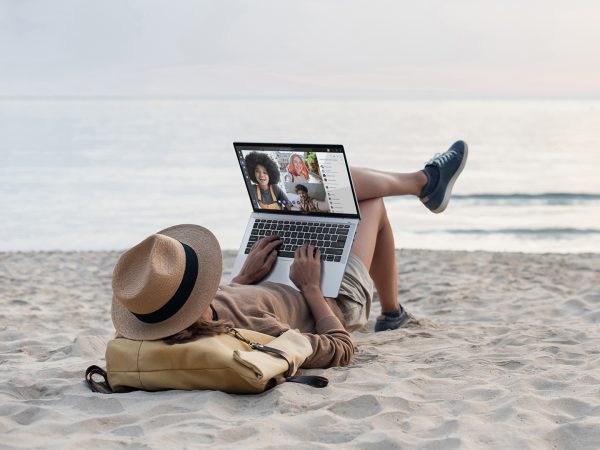 Man sitting back on the beach looking at his laptop computer