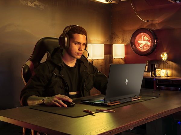 Man sitting at a desk with headphones on playing video games on a laptop