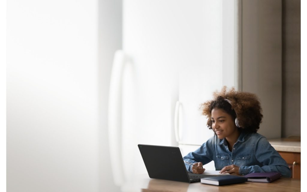 Student wearing headphones and working on an Acer TravelMate B3 11