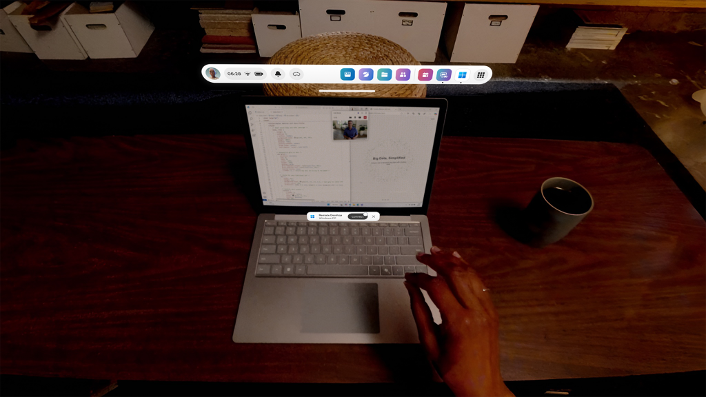 A first-person mixed reality view of a living room's wooden coffee table with a laptop. Over the laptop's keyboard, a button with the Windows App logo and a 'Connect' label is displayed. A hand reaches forward, pinching to select the 'Connect' button.