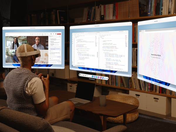 A person wearing a Meta Quest 3S mixed reality headset sits on a couch in a living room, interacting with three large virtual monitors floating in front of them. The monitors display a video conference, a coding editor, and a data visualization webpage. A laptop and a coffee cup are on the wooden coffee table in front of them, with a bookshelf in the background.