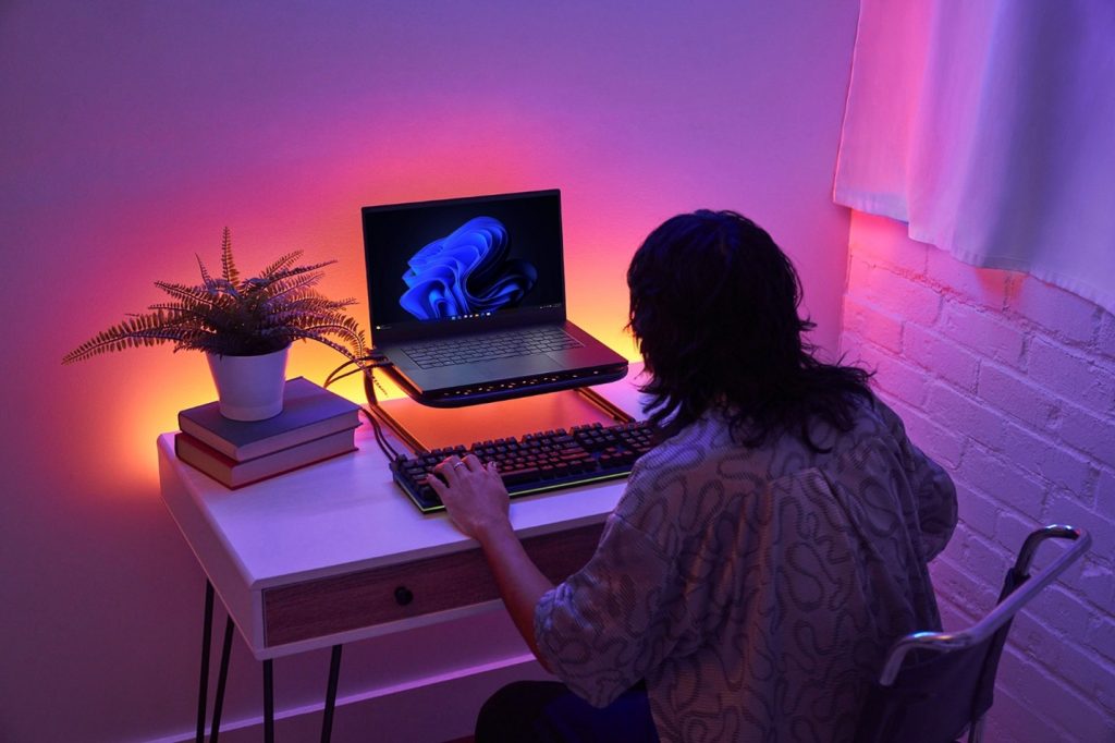 Person working at a laptop computer illuminated by colorful lighting