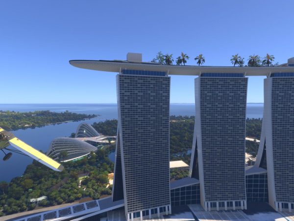 Plane flying over water toward three high rises connected by a rooftop pool