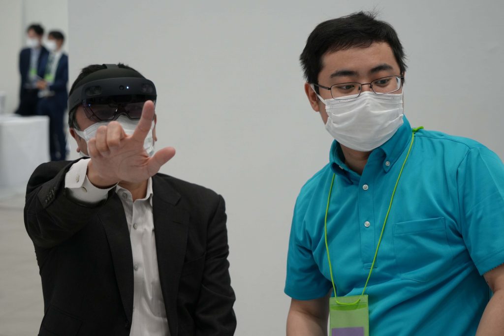 HoloLens 2 を装着して体験する人と、ガイドするスタッフの様子