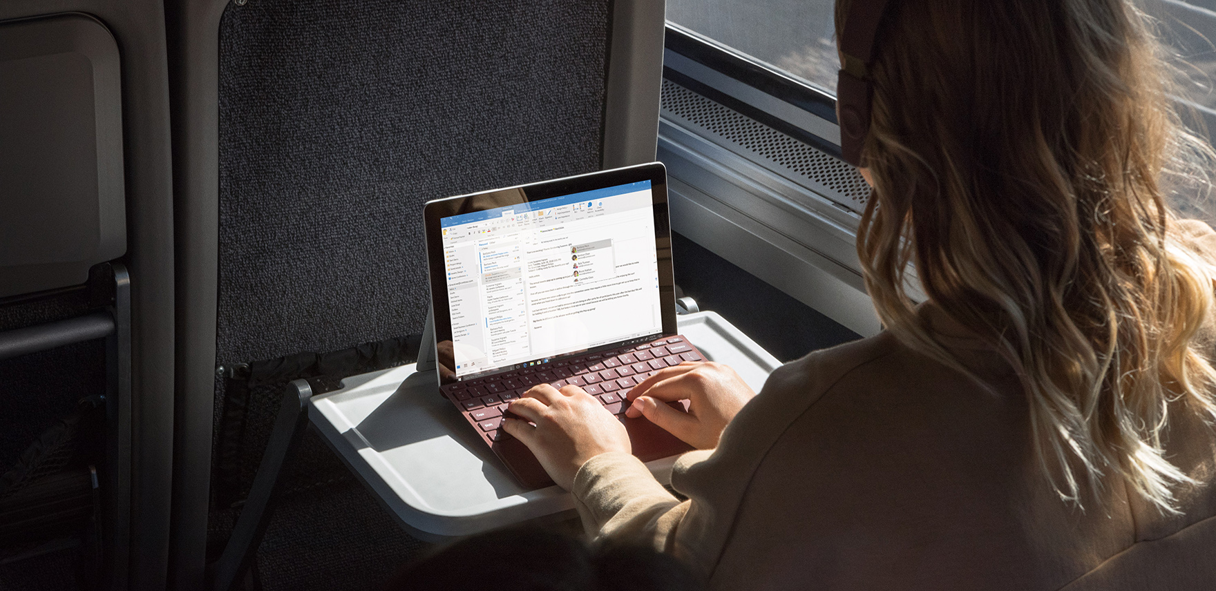 Woman on a train working on a Surface Go