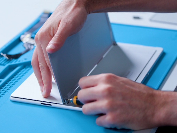 Person's hands replacing the kickstand on Surface Pro 9