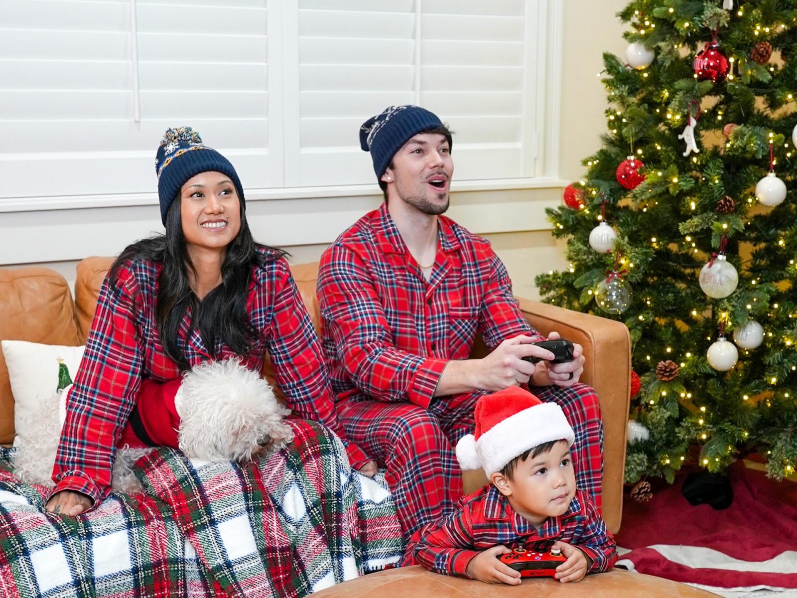 Mother, father and child enjoy a computer game together next to a Christmas tree