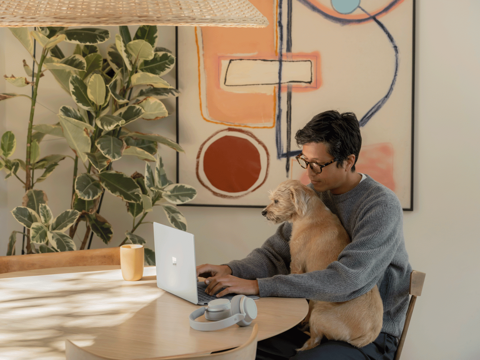 una persona trabaja en una computadora con un perro en su regazo